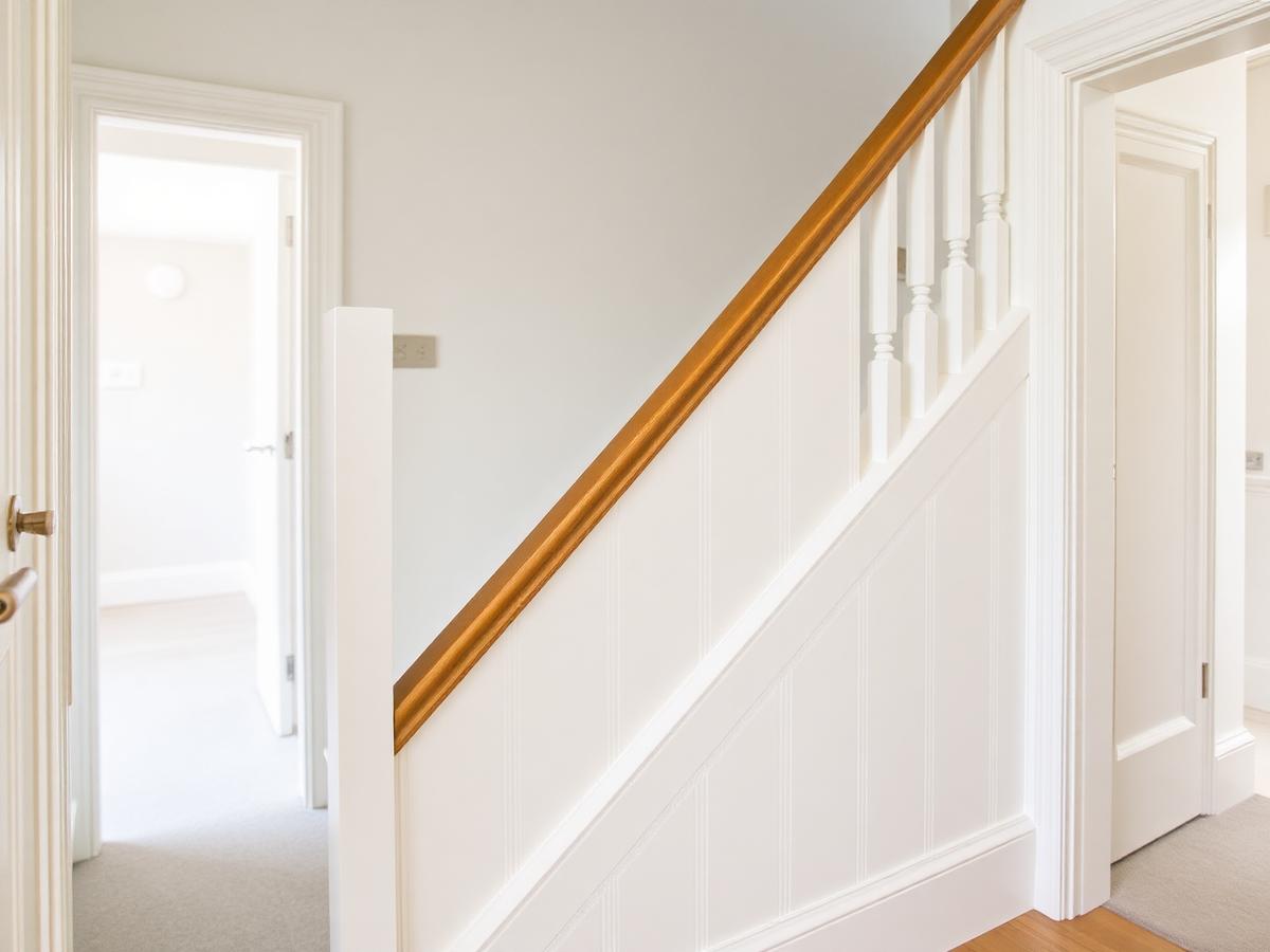 Newly fitted staircase panelling, oak handrail, skirting and architrave in a bright hallway